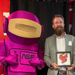Man standing with astronaut mascot